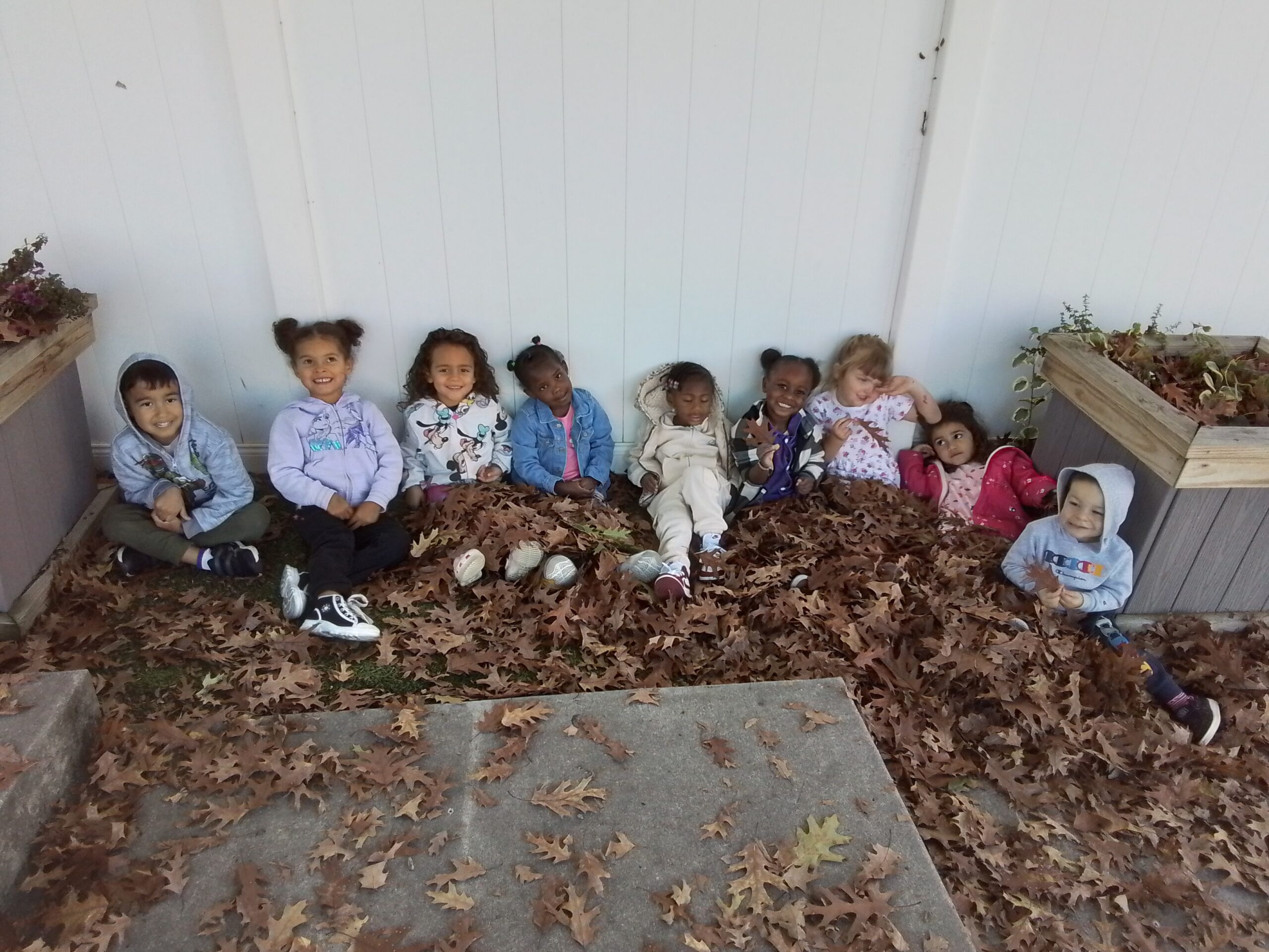 Preschool children playing in leaves at Lancaster Early Education Center